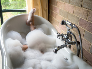 Men's  feet covered with foam bubble bath  in luxury bathtub with happiness and relaxing