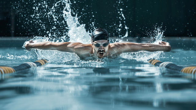 The dynamic and fit swimmer in cap breathing performing the butterfly stroke at pool. The young man. The fitsport, swimmer, pool, healthy, lifestyle, competition, training, athlete, energy concept