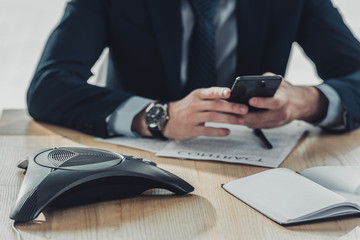 cropped shot of businessman using smartphone at workplace