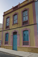 Fototapeta na wymiar A 19th century pink and yellow building with a blue door and five windows in Santa Cruz de Tenerife, Spain