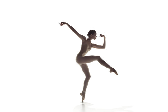Young graceful female ballet dancer or classic ballerina dancing isolated on white studio. Caucasian model on pointe shoes