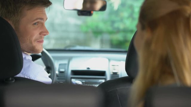Female taxi passenger sitting inside car, driver smiling, urban trip, carpool