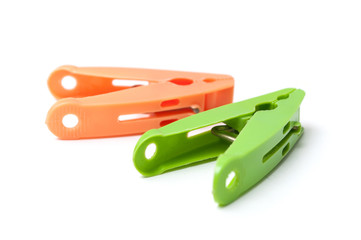 closeup of green and orange plastic clothespins on white background