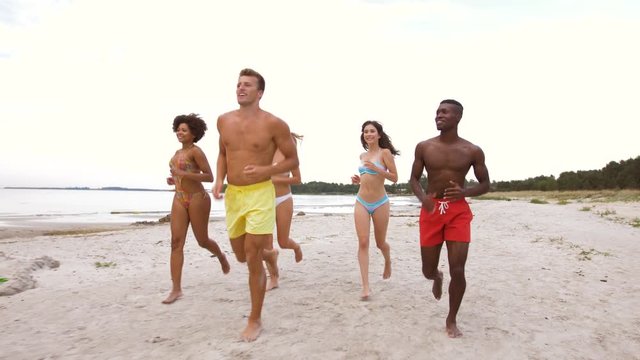 friendship, summer holidays and people concept - happy friends running on beach
