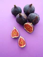 Fresh ripe figs on a purple background. Food photo. Sweet sliced figs on a table. Top view. Copy space.