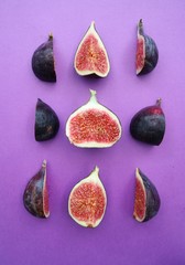 Fresh ripe figs on a purple background. Food photo. Sweet sliced figs on a table. Top view. Copy...