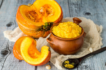      Clay pot with millet porridge and a ripe fresh pumpkin on a napkin on an old wooden table. 