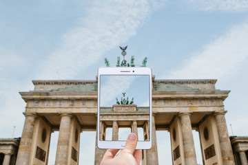 The tourist photographs on the tablet Brandenburg Gate in Berlin. Traveling in Germany. Sightseeing.