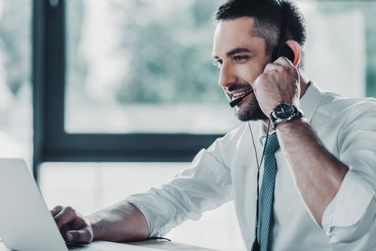 smiling adult support hotline worker with laptop at workplace