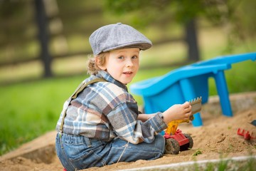 Small caucasian boy playing in sandpit