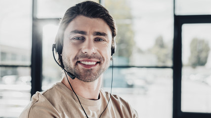 close-up portrait of smiling young support hotline worker with headphones