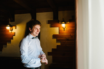 A man in a shirt and tie adjusts the watch on his arm at home. businessman using watch.