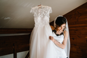 The bride holds a wedding dress in her hands and spins, turn with her on the bed. Style vintage...