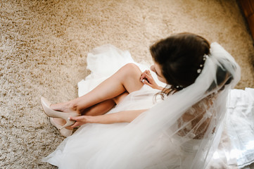 Bride putting on her stylish classic lacquered beige shoes. Elegant Female puts hands on shoes on a...