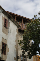 Fototapeta na wymiar A polished wood balcony of a stone house, with a green tree and a blue sky