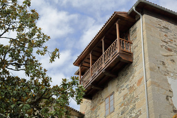 Fototapeta na wymiar A polished wood balcony of a stone house, with a green tree and a blue sky