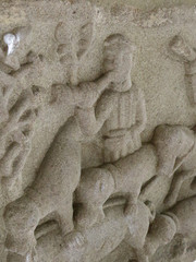 Fototapeta na wymiar A close view of a stone low relief of a man playing a horn with some dogs during a hunt