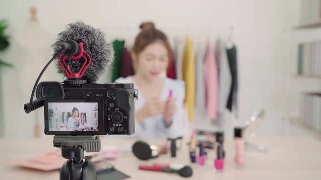 Beauty blogger present beauty cosmetics while sitting in front camera for recording video. Beautiful woman use brush while review make up tutorial broadcast live video to social network by internet.