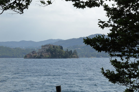 A landscape of Orta San Giulio island in the Orta Lake, in the Novara province in northern Italy, with branches and leaves of a tree