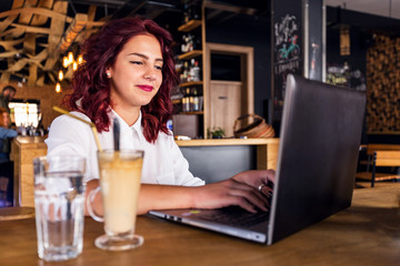 Young student girl working with laptop at coffee shop