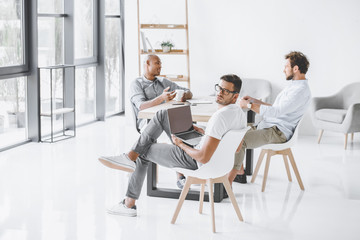 multicultural group of businessmen sitting at workplace in light modern office