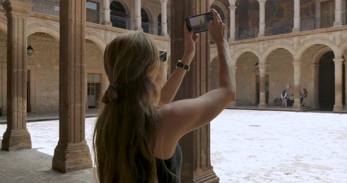 Woman tourist taking photos with her smart phone in a historic building