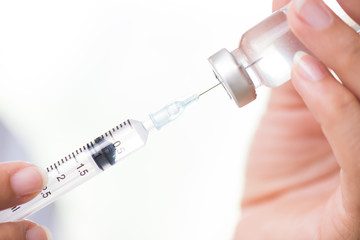 Female doctor with a stethoscope on shoulder holding syringe and vaccine. Healthcare And Medical concept.