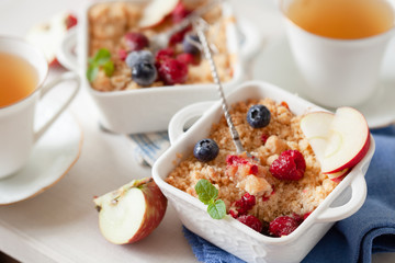Traditional British apple crumble on portion baking dish with fresh berries