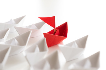 Leadership concept. red paper ship lead among white. One leader ship leads other ships.