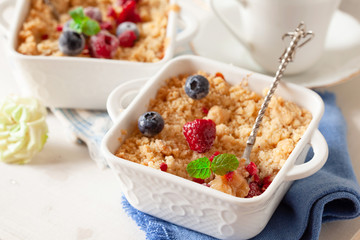 Traditional British apple crumble on portion baking dish with fresh berries