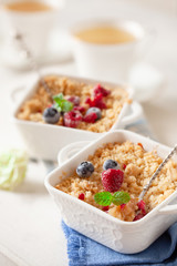 Traditional British apple crumble on portion baking dish with fresh berries