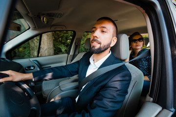 Taxi driver driving a car with businesswoman