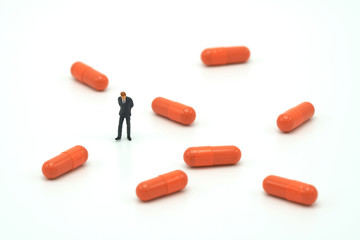 Miniature people businessmen standing and orange capsule medicine. on white background using as background business concept and Health concept with copy space.