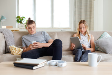 Brother and sister using technologies at home