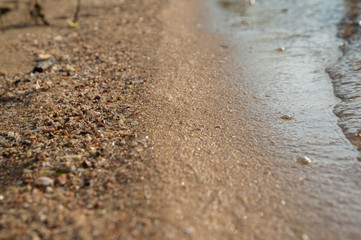 Fototapeta na wymiar River blue waves and white foam on the sandy beach. Close-up.