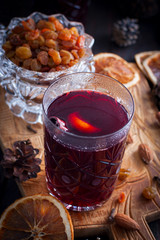 Scandinavian hot alcoholic drink with cinnamon in a glass cup on a wooden board, selective focus
