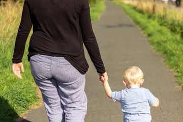 Mother holding sons hand walking down long road