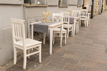 Terraza de bar con mesas y sillas blancas.