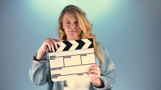 Beautiful long-haired woman holding clapper-board and looking into camera, hobby
