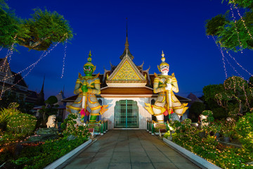 Wat Arun Raj Tharam - Two giant statues holding their batons in front of the temple entrance. Giant green Todsagun the giant white millenium splendor of the Ramayana