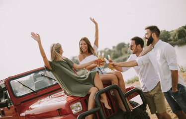Young people drinking and having fun by car