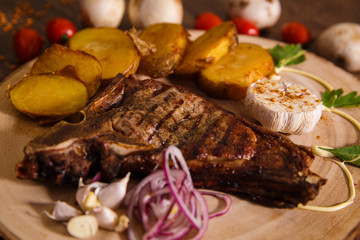 steak t-bone on wooden backing and baked potatoes