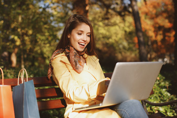 Young woman online shopping via laptop in the park