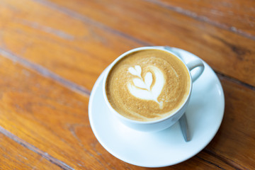 A cup of coffee latte on the wood table.