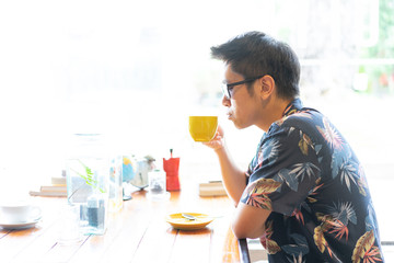 A hipster boy with sunglasses is drinking hot coffee.