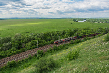 Obraz premium Pociąg towarowy z lokomotywami przejeżdżającymi koleją w Rosji, wzdłuż typowego rosyjskiego krajobrazu, widok z góry