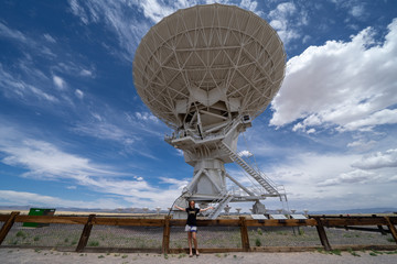 Adult woman poses to show scale of the Very Large Array located in New Mexico
