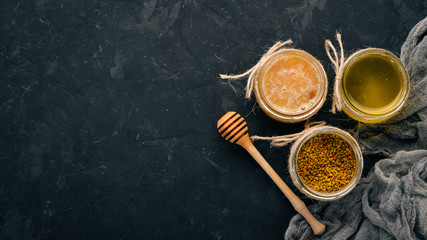 A set of beekeeping products and honey on a black stone background. Free space for text. Top view.