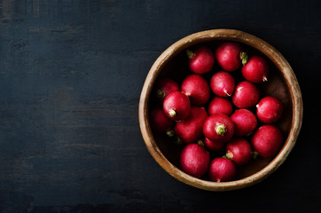 Radishes Filling Old Wooden Bowl on Grungy Black Surface from Above