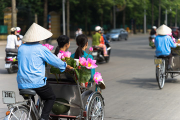 Fototapeta na wymiar Cyclo (pedicab) driver wears conical hat on Hanoi street